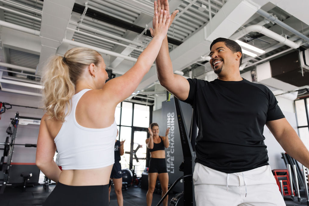 Man and woman high-fiving between stations during a group workout.